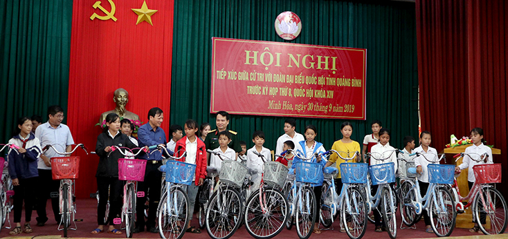 Các đại biểu Quốc hội tặng xe đạp cho các em học sinh nghèo tại huyện Minh Hóa.    