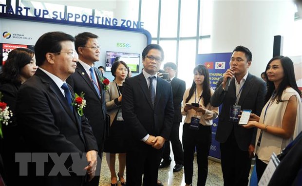 Phó Thủ tướng Trịnh Đình Dũng (ngoài cùng, bên trái) và đại biểu nghe giới thiệu sản phẩm công nghệ Hàn Quốc tại gian trưng bày sản phẩm trong khuôn khổ hội nghị. (Ảnh: Trần Tĩnh/TTXVN)