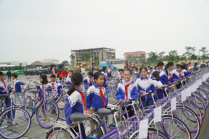 Các em HS phấn khởi khi được nhận những chiếc xe đạp màu tím.