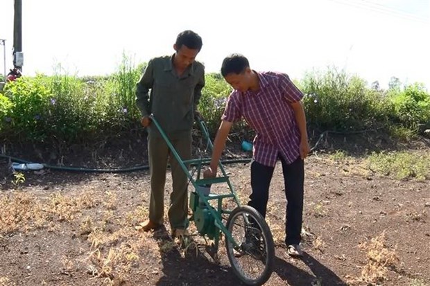 Anh Nguyễn Văn Anh (phải) hướng dẫn người dân sử dụng máy gieo hạt và bón phân. (Ảnh: Lê Xuân/TTXVN)