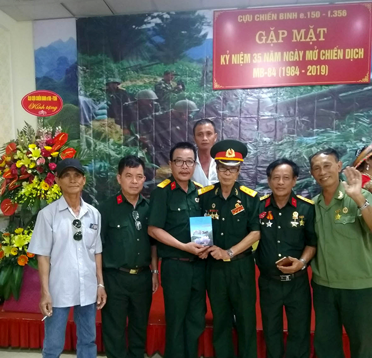  Trung tá Đặng Xuân Nghiêm (giữa), nguyên Trung đoàn trưởng 150 sư đoàn 356 tặng sách cho đoàn CCB Mặt trận Vị Xuyên Bình Trị Thiên nhân gặp mặt kỷ niệm 35 năm chiến dịch MB84 (12-7-1984 - 12-7-2019).