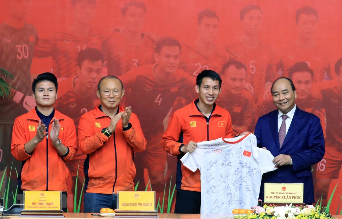 Tiền vệ Đỗ Hùng Dũng, thay mặt đội tuyển bóng đá U22 nam tặng Thủ tướng Nguyễn Xuân Phúc chiếc áo đấu có chữ ký của các cầu thủ và Ban huấn luyện. (Ảnh: Thống Nhất/TTXVN)