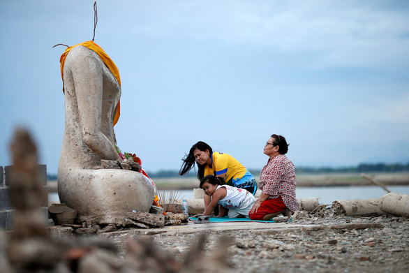 Một gia đình người Thái đến cầu nguyện bên tượng Phật mất đầu. Tượng này trồi lên từ đáy sông do hạn hán làm nước khô cạn ở Lopburi, Thái Lan. Ảnh do Soe Zeya Tun chụp ngày 1-8-2019. Gần cuối tháng 11-2019, Ủy hội Sông Mekong (MRC) đã đưa ra cảnh báo về tình trạng hạn hán nghiêm trọng đến cực đoan có thể sẽ xảy ra tại các quốc gia ở hạ lưu sông Mekong cho tới tháng 1-2020, trong đó Thái Lan và Campuchia bị hạn nghiêm trọng nhất. Phân tích sơ bộ dữ liệu của MRC cho thấy nguyên nhân dẫn đến đợt hạn này là do lượng mưa thấp trong mùa mưa, cùng với việc mưa gió mùa bắt đầu muộn và kết thúc sớm và do hiện tượng El Nino đã làm nhiệt độ cao bất thường và nước bốc hơi với lượng lớn - Ảnh: REUTERS