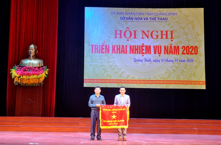 Đồng chí Phó Chủ tịch UBND tỉnh Trần Tiến Dũng trao cờ thi đua của Bộ trưởng Bộ VH-TT-DL cho Trung tâm văn hóa Thông tin huyện Tuyên Hóa.