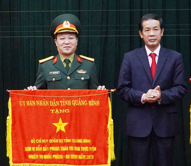 Đồng chí Chủ tịch UBND tỉnh Trần Công Thuật tặng cờ đơn vị dẫn đầu phong trào thi đua thực hiện nhiệm vụ quốc phòng-an ninh năm 2019 cho Bộ CHQS tỉnh. 