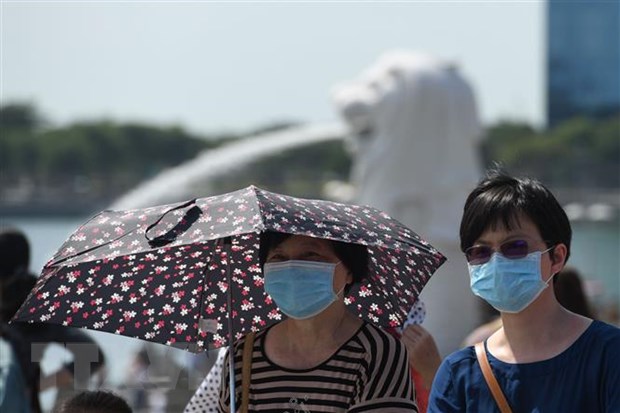  Khách du lịch đeo khẩu trang để phòng tránh lây nhiễm virus corona chủng mới tại Singapore. (Ảnh: AFP/TTXVN)