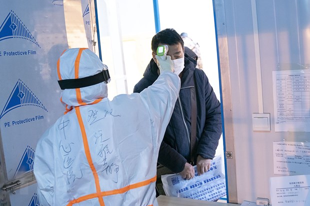 Nhân viên y tế kiểm tra thân nhiệt cho bệnh nhân nhiễm Covid-19 tại một bệnh viện dã chiến ở Vũ Hán, Trung Quốc ngày 5-2-2020. (Nguồn: THX/TTXVN)
