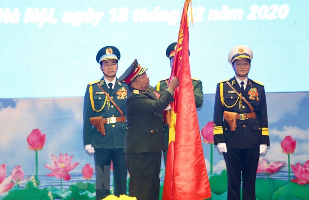 Đại tướng Chansamone Chanyalath, Bộ trưởng Bộ Quốc phòng CHDCND Lào gắn Huân chương Tự do hạng Nhất lên cờ truyền thống của Quân đội nhân dân Việt Nam. (Ảnh: Dương Giang/TTXVN)
