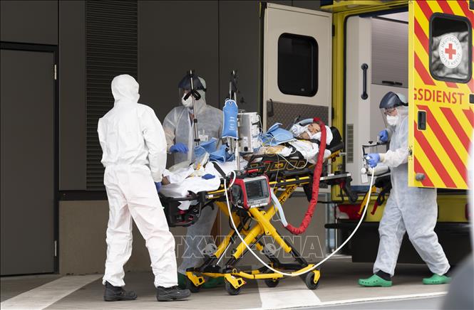  Nhân viên y tế chuyển bệnh nhân mắc COVID-19 từ xe cứu thương vào một bệnh viện ở Dresden, Đức ngày 26-3-2020. Ảnh: AFP/TTXVN