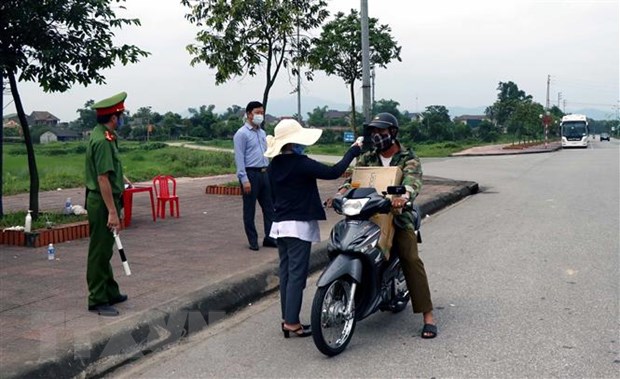   Lực lượng chức năng kiểm tra thân nhiệt người đi đường tại thành phố Hà Tĩnh. (Ảnh: Công Tường/TTXVN)