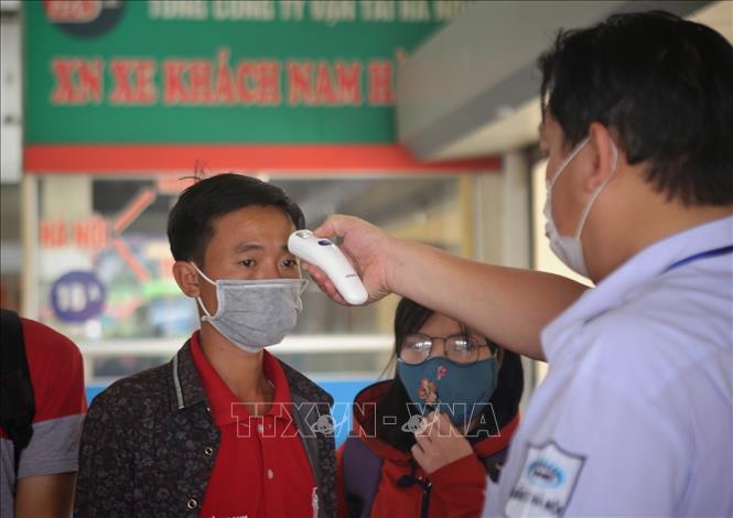  Kiểm tra thân nhiệt cho người dân phòng chống dịch COVID-19 tại các bến xe khách. Ảnh: TTXVN