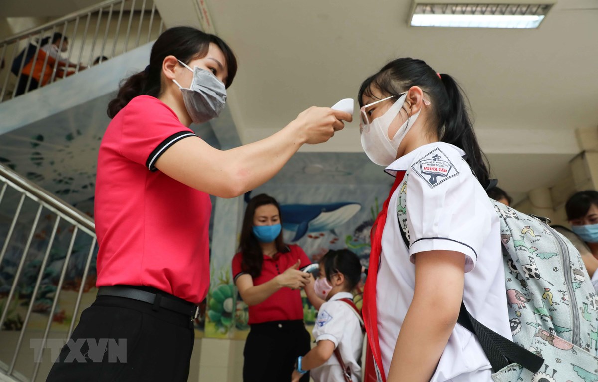 Học sinh trường Tiểu học Nghĩa Tân, quận Cầu Giấy được đo thân nhiệt và sát khuẩn tay trước khi vào lớp. (Ảnh: Thanh Tùng/TTXVN)