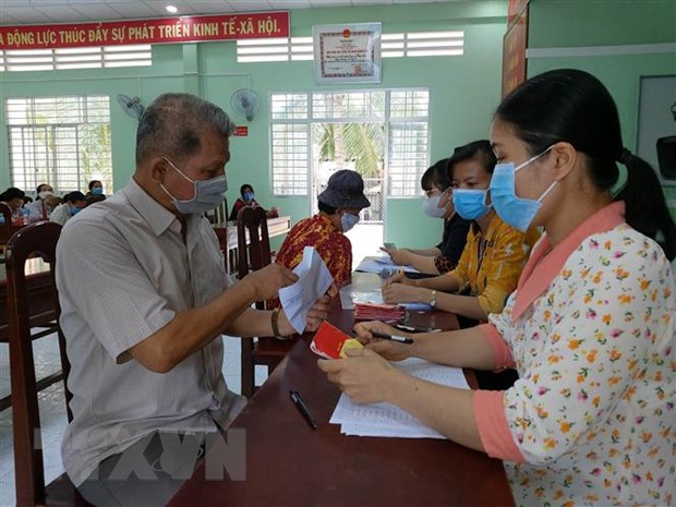 Người dân xã Thành An, huyện Mỏ Cày Bắc, Bến Tre nhận tiền hỗ trợ. (Ảnh: Trần Thị Thu Hiền/TTXVN)