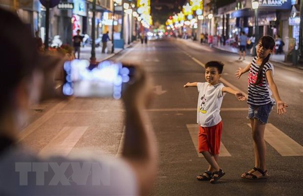 Người dân Thủ đô ghi lại những hình ảnh đáng nhớ trên phố đi bộ hồ Hoàn Kiếm ngày hoạt động trở lại. (Ảnh: Thành Đạt/TTXVN)