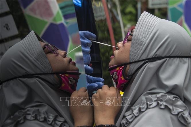  Nhân viên y tế lấy mẫu xét nghiệm COVID-19 cho người dân ở Surabaya, Indonesia ngày 20-5. Ảnh: AFP/TTXVN