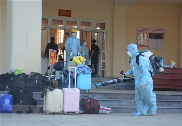 Nhân viên y tế phun thuốc khử trùng vào các vật dụng, hành lý của công dân từ Hàn Quốc trở về. (Ảnh: Văn Dũng/TTXVN)