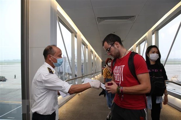 Nhân viên y tế kiểm tra phiếu khai báo y tế của hành khách trước khi làm thủ tục nhập cảnh tại cửa khẩu Sân bay quốc tế Nội Bài, Hà Nội, chiều 7/3 vừa qua. (Ảnh: Dương Giang/TTXVN)