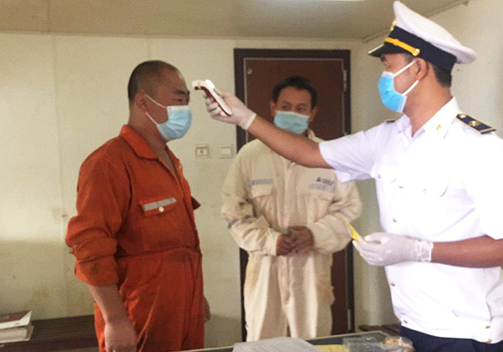 Cán bộ trung tâm phòng chống bệnh tật tỉnh Quảng Bình đo thân nhiệt, kiểm tra sức khỏe các thuyền viên tàu Amoy Dream 