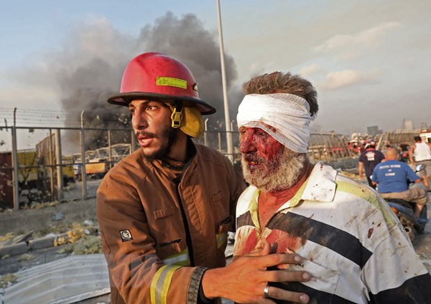 Lính cứu hỏa trợ giúp một nạn nhân bị thương trong vụ nổ kinh hoàng ở Beirut, Liban ngày 4-8-2020. (Ảnh: AFP/TTXVN)