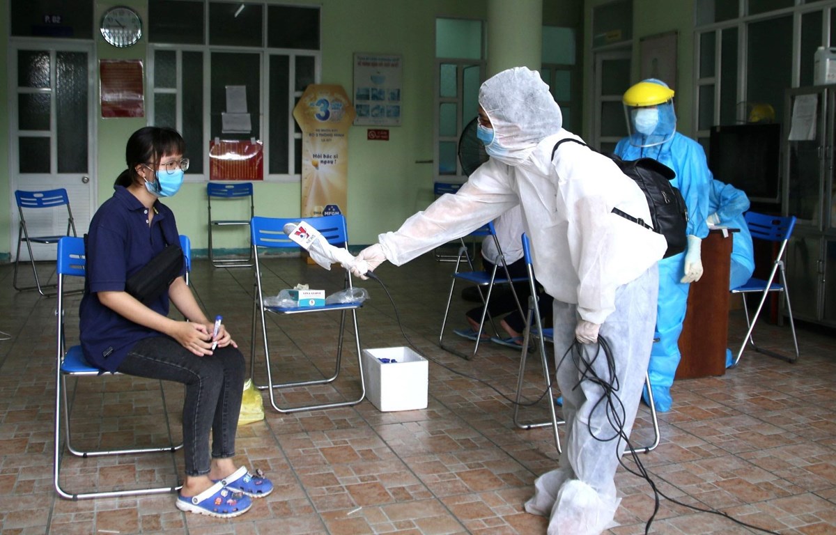 Phóng viên Kênh truyền hình Thông tấn Vnews tác nghiệp an toàn tại khu vực có nguy cơ lây nhiễm. (Ảnh: Quốc Dũng/TTXVN)