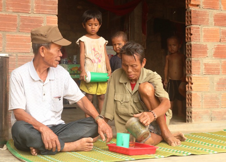  Ông Hồ Hơn (người ngồi bên trái) trò chuyện với bà con ở bản Lâm Ninh.