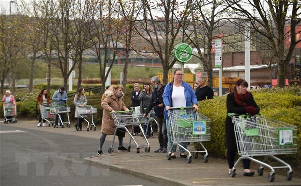 Người dân xếp hàng chờ mua sắm bên ngoài một siêu thị ở Gateshead, Anh. (Ảnh: AFP/TTXVN)