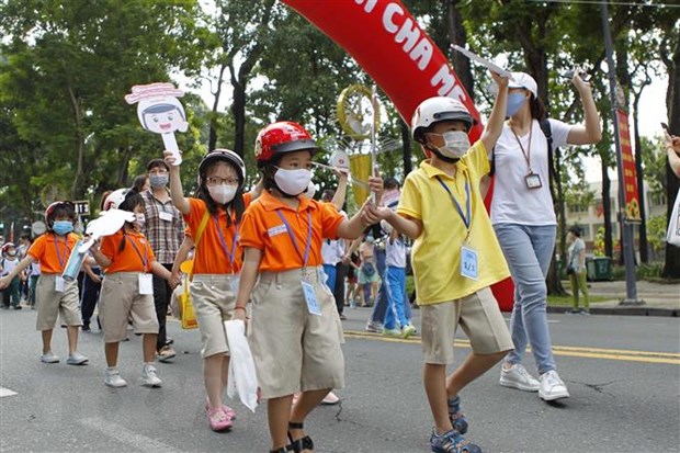 Các em học sinh tiểu học cùng phụ huynh và thầy cô giáo đi bộ vận động toàn dân 'Đội mũ bảo hiểm cho trẻ em' trên đường Lê Duẩn, quận 1, Thành phố Hồ Chí Minh. (Ảnh: Thanh Vũ/TTXVN)