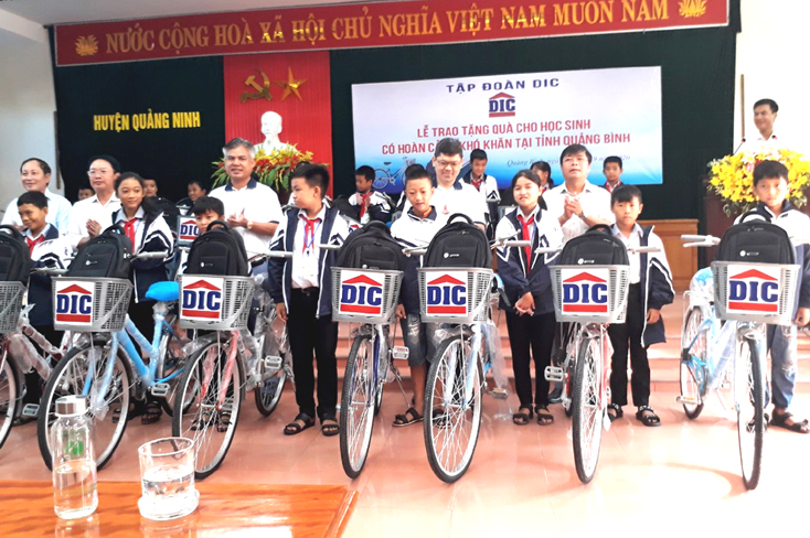 Đại diện lãnh đạo Tập đoàn DIC và huyện Quảng Ninh tặng xe đạp cho học sinh nghèo vượt khó.