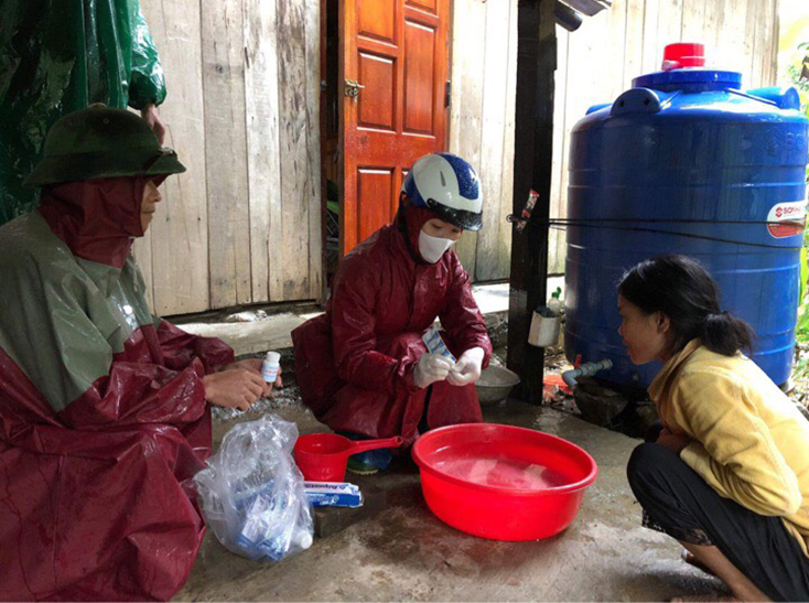 Cán bộ Trung tâm Y tế huyện Minh Hóa đang hướng dẫn người dân xử lý nguồn nước sinh hoạt tại tâm lũ xã Tân Hóa.              