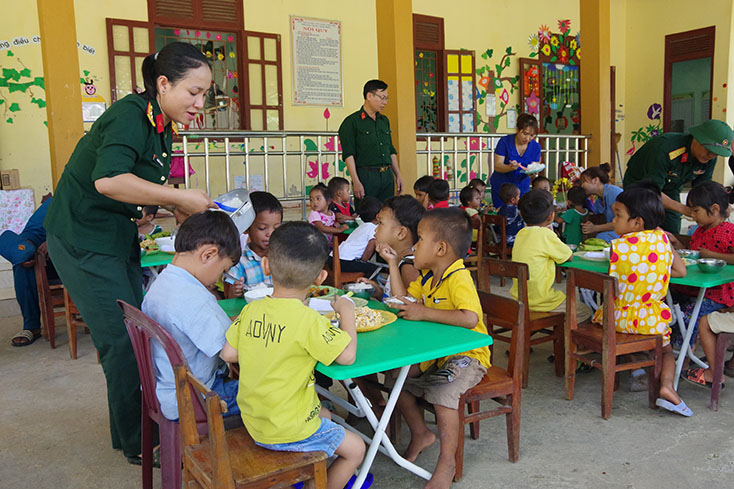 Cán bộ, chiến sỹ Ban chỉ huy Quân sự huyện Lệ Thủy tổ chức bữa cơm cho học sinh điểm trường mầm non bản Bạch Đàn, xã Lâm Thủy. 