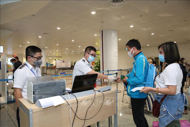 Nhân viên y tế kiểm tra phiếu khai báo y tế của hành khách trước khi làm thủ tục nhập cảnh tại cửa khẩu Sân bay quốc tế Nội Bài (Hà Nội). Ảnh minh họa: Dương Giang/TTXVN