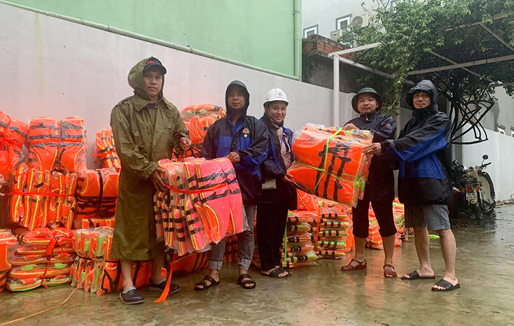 Đại diện lãnh đạo Công ty TNHH nông nghiệp công nghệ cao Tuệ Lâm trao áo phao hỗ trợ cho người dân vùng lụt.