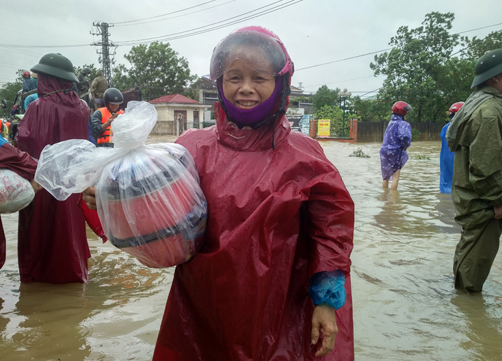 Mệ Trần Thị Láng, thôn Thạch Bàn (xã Phú Thủy) và thùng cơm đưa tặng bà con vùng lũ lụt tại điểm trung chuyển hàng hóa chợ Đôộng