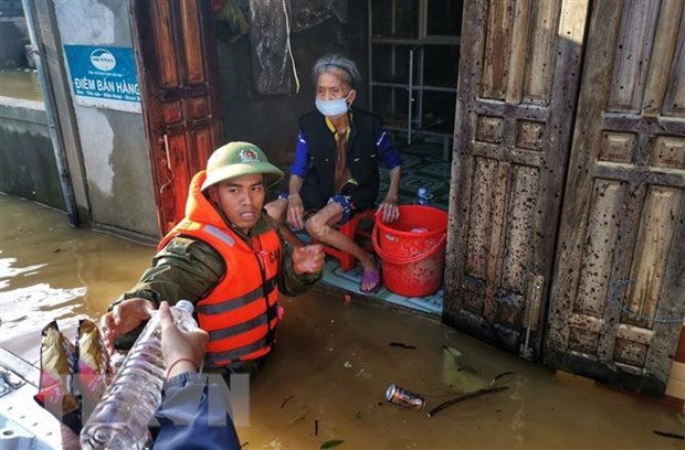 Lực lượng công an huyện Lệ Thủy lội nước, đưa hàng cứu trợ đến những gia đình bị cô lập trong nước lũ. (Ảnh: TTXVN)