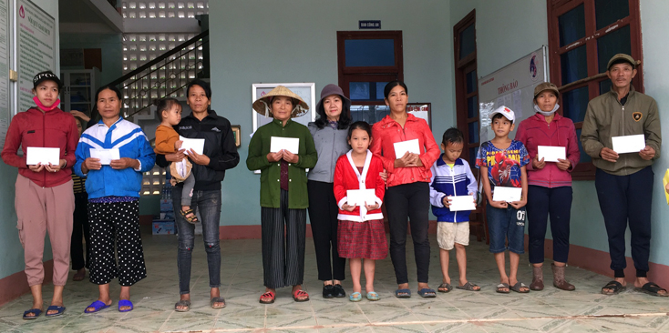 Đại diện phóng viên Báo Quảng Bình trao tiền hỗ trợ cho các hộ dân bị thiệt hại nặng ở thôn Liên Thủy, xã Liên Trạch, huyện Bố Trạch.