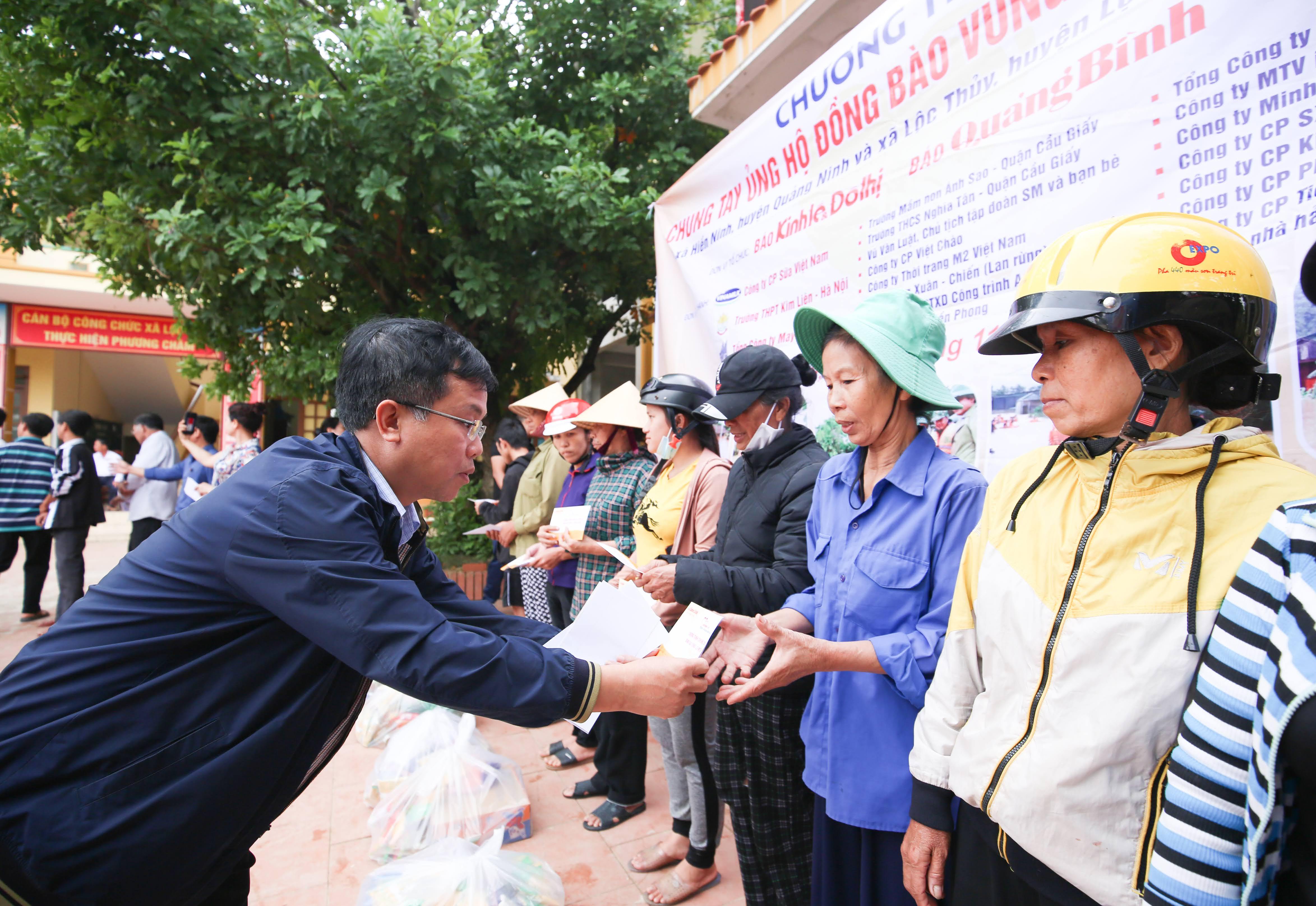 Nhà báo Lại Bá Hà, Phó Tổng biên tập Báo Kinh tế và Đô thị trao quà cho bà con vùng lũ xã Lộc Thủy, huyện Lệ Thủy.