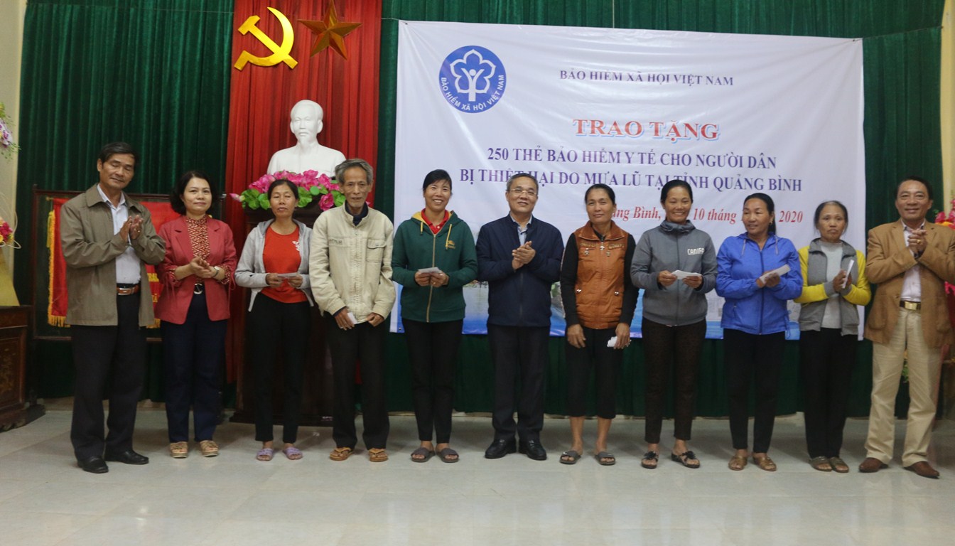 Phó Tổng Giám đốc BHXH Việt Nam Phạm Lương Sơn và Giám đốc BHXH Quảng Bình trao tặng thẻ BHYT cho bà con vùng lũ huyện Lệ Thủy.