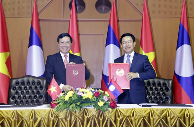 Phó Thủ tướng, Bộ trưởng Ngoại giao Phạm Bình Minh (trái) và Bộ trưởng Ngoại giao Lào Saleumsay Kommasith đang trao cho nhau Thỏa thuận hợp tác giữa Bộ Ngoại giao Việt Nam và Bộ Ngoại giao Lào giai đoạn 2021-2025. (Ảnh: Phạm Kiên/TTXVN)