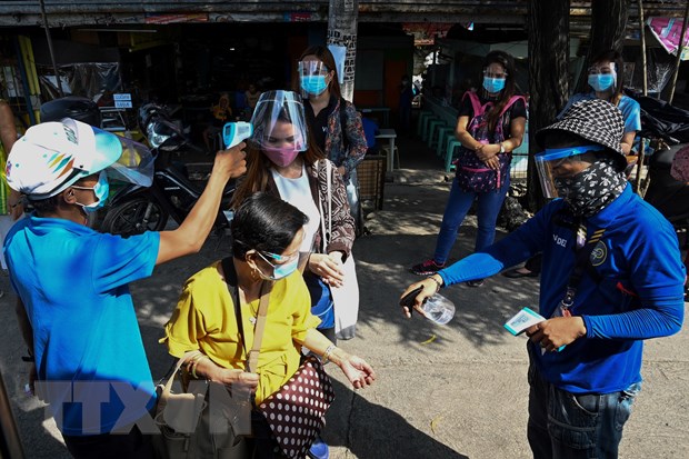 Kiểm tra thân nhiệt cho hành khách trước khi lên xe buýt tại Manila, Philippines. (Ảnh: AFP/TTXVN)