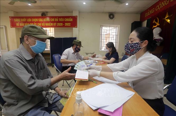 Người có công với cách mạng, hộ nghèo, hộ cận nghèo, đối tượng hưởng bảo trợ xã hội ở phường Mai Động, quận Hoàng Mai, Hà Nội nhận tiền hỗ trợ từ gói hỗ trợ 62.000 tỷ đồng. Ảnh: Trần Việt/TTXVN