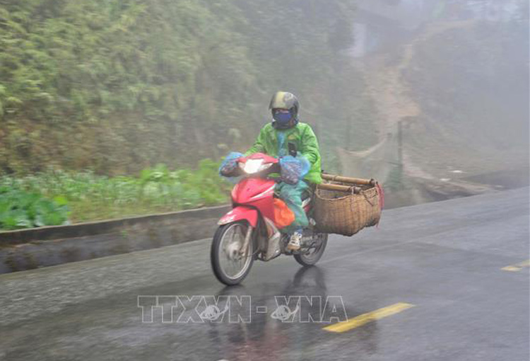  Người dân đi xe máy vận chuyển hàng hóa trong sương sớm, giá lạnh trên đỉnh đèo Pha Đin (Điện Biên). Ảnh: Xuân Tiến-TTXVN