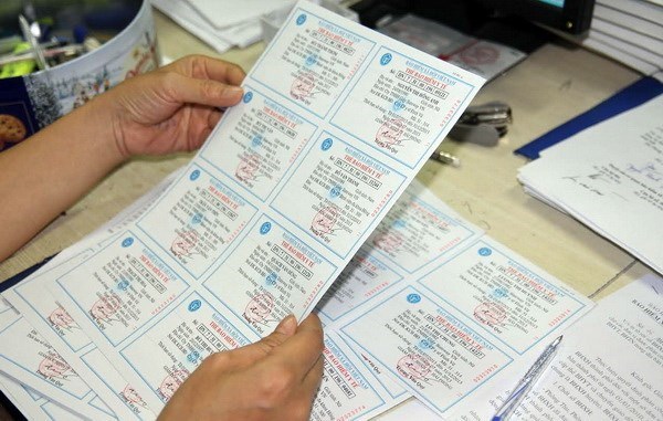  Kiểm tra thẻ bảo hiểm y tế trước khi phát cho người dân. (Ảnh: PV/Vietnam+)
