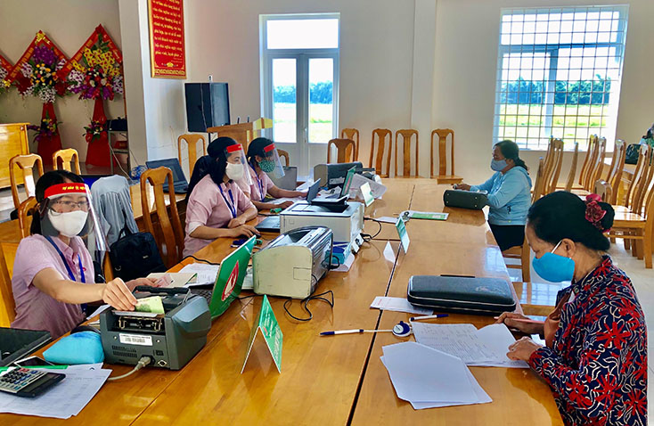 Cán bộ PGD NHCSXH huyện Quảng Ninh hỗ trợ người dân làm thủ tục vay vốn tại các điểm giao dịch xã.