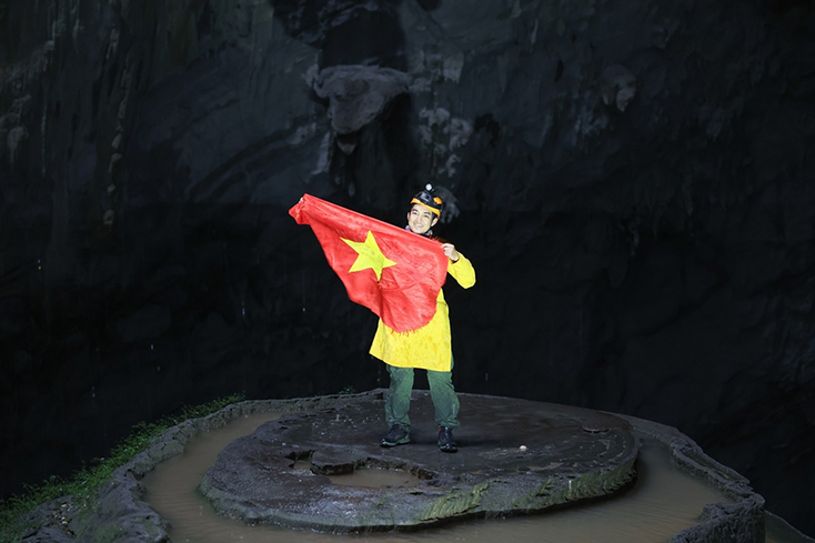 Đăng Khoa chụp ảnh kỷ niệm với Quốc kỳ Việt Nam và trang phục áo dài truyền thống ở hang Sơn Đoòng. (Ảnh: Nhân vật cung cấp)