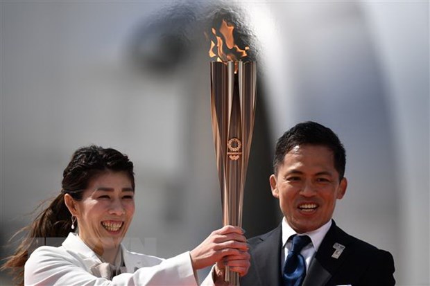 Vận động viên Nhật Bản ba lần giành Huy chương Vàng Olympic Saori Yoshida (trái) và Tadahiro Nomura (phải) giơ cao ngọn đuốc Olympic Tokyo 2020 sau khi đuốc được chuyển về từ Hy Lạp, tại căn cứ không quân Matsushima ở Higashimatsushima, tỉnh Miyagi ngày 20-3-2020. (Ảnh: AFP/TTXVN)