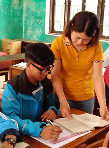 Hồ Văn Trọng đang được giáo viên hướng dẫn trong một tiết học ở trường. 