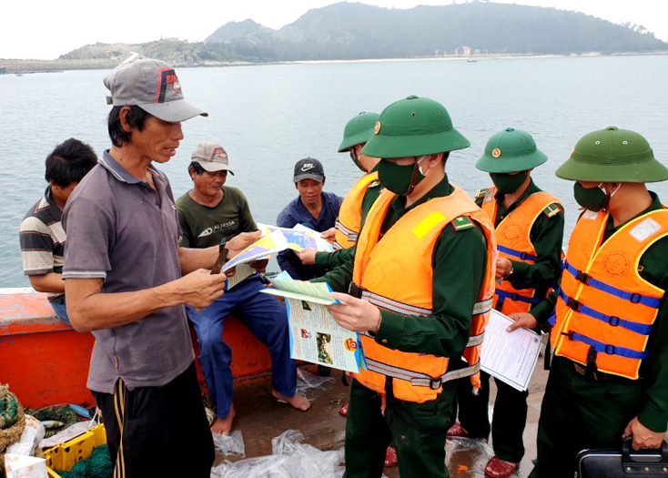 Cán bộ Đồn Biên phòng Roòn phát tờ rơi tuyên truyền cho ngư dân trên địa bàn về phòng chống khai thác IUU.