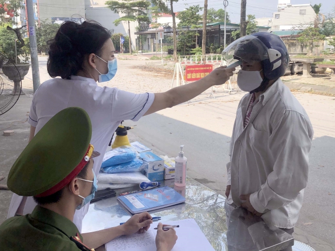  Đo thân nhiệt cho người dân tại một chốt cách ly y tế tại khu đô thị Đồng Sơn, thành phố Phúc Yên (Vĩnh Phúc). Ảnh: Hoàng Hùng - TTXVN