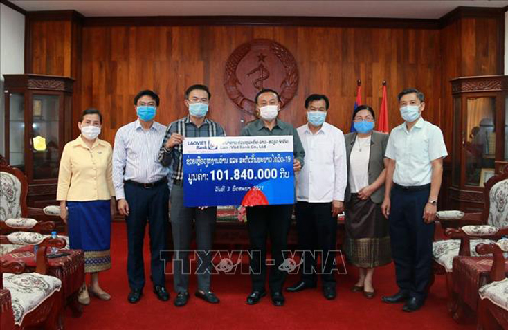 Tổng Giám đốc LaoVietBank Nguyễn Đức Vũ (trái) trao tượng trưng tiền tài trợ cho Đại diện Bộ Y tế Lào. Ảnh: Phạm Kiên/Pv TTXVN tại Lào.