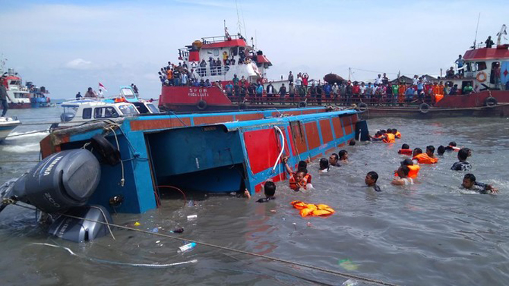 Các thành viên của đội tìm kiếm và cứu hộ Indonesia cố gắng giúp đỡ hành khách từ một chiếc thuyền bị lật ở Tarakan vào ngày 25-7-2017. Ảnh (tư liệu): AFP